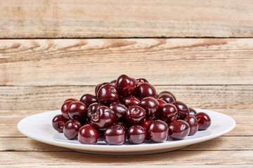 cherry in a white plate on a wooden background