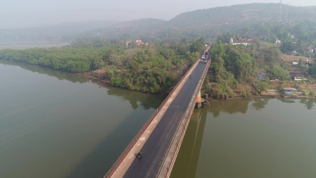 Aerial view. Flying over the bridge,cars goes on a large concrete bridge across the river. 