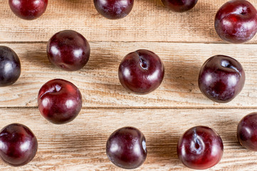 several plums are scatter on wooden background