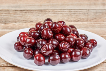 cherry in a white plate on a wooden background