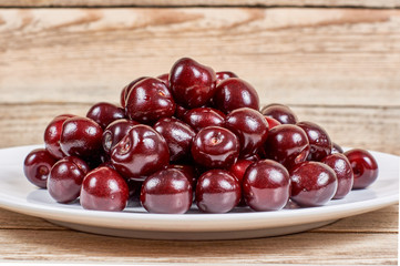 cherry in a white plate on a wooden background