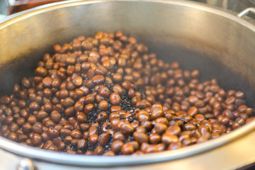 Roasting chestnuts with traditional in Thailand. Roasted brown chestnuts sold in street by street vendors. Roasted chestnut is a popular autumn and winter street food in East Asia and Europe.