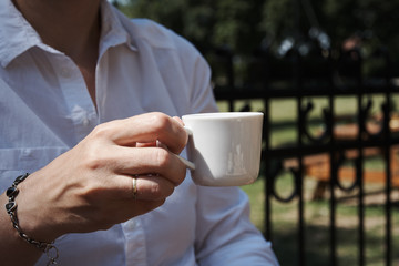 Young woman holding a cup of coffee in the garden on a sunny day