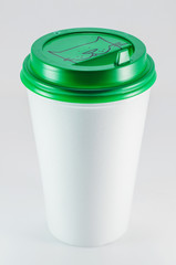 white plastic coffee cup with green lid on white background, view from above with copy space