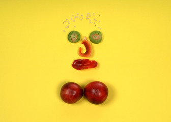 sad face made with various raw vegetables, a smiley face on a yellow background.