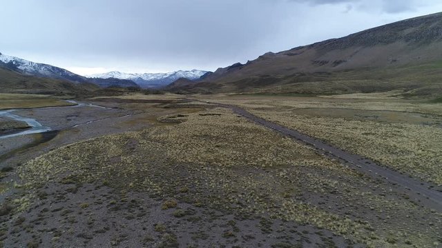Aerial drone scene of The Andes mountains, in Mendoza, Cuyo Argentina. Patagonia steppe landscape. Camera going forwards over a gravel lonely road and van with trailer, motorhome, appears.
