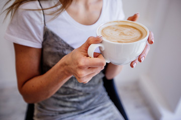 Cup of cappuccino in hand beautiful girl.