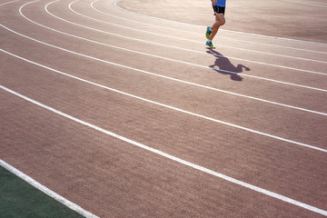 Athletic man in colorful sneakers run on running track stadium