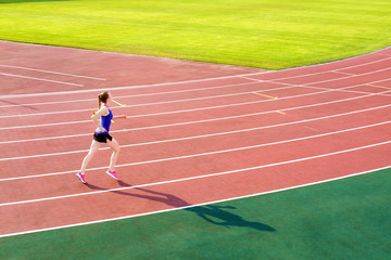 Athletic young woman in pink sneakers run on running track stadium