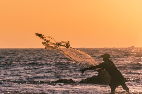 Local fisherman casts fishing net, backlit, sunset, Chaung Thar Beach, Bay of Bengal, Ayeyarwady, Myanmar, Asia