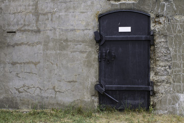 black metal door on old concrete wall