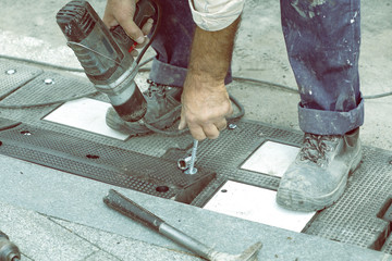 Worker hand screws a screw in a rubber board 3