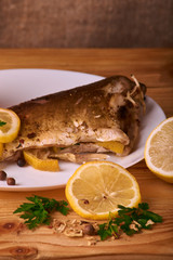 Grilled fish with herbs and lemon on wooden background. Mediterranean luxurious seafood concept