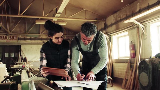 Man and woman workers with tablet in the carpentry workshop.