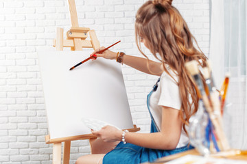 Pretty talented female painter painting on easel