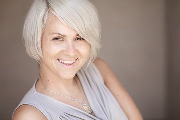 Beautiful blond caucasian woman with stylish haircut looking cheerfully in the camera on a blurred blue background