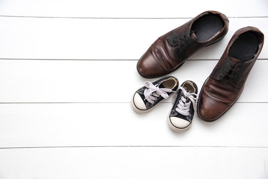 The shoes of father and son on wood white background - concept take care