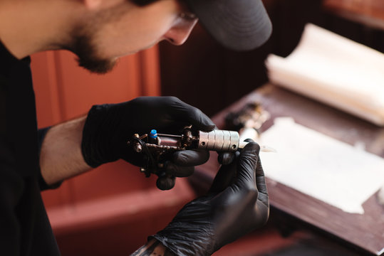 selective focus of tattoo artist in gloves with tattooing machine in salon