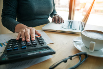 Business women are using a calculator to calculate the income of the business.