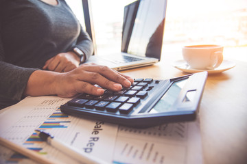 Business women are using a calculator to calculate the income of the business.