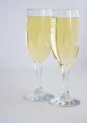 two glasses with champagne on a white background.