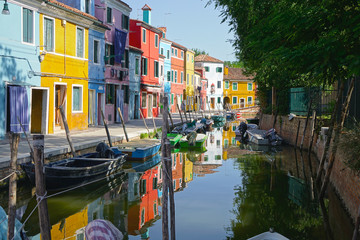 Fototapeta na wymiar Walking over a narrow calm channel running through the vivid streets of Venice.