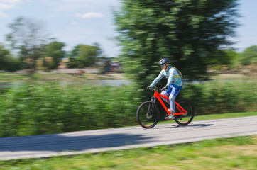 A cyclist in a helmet rides a bicycle path, motion blur