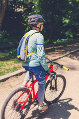 Fototapeta premium Cyclist in helmet on orange bike riding in park