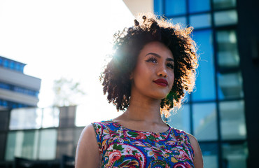 Beautiful latin woman with curly hair, portrait set in the city - obrazy, fototapety, plakaty