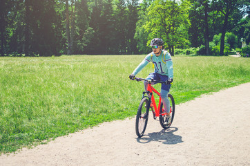 Fototapeta premium Cyclist in helmet on orange bike riding in park