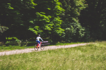 Naklejka premium A cyclist in a helmet rides a bicycle path, motion blur