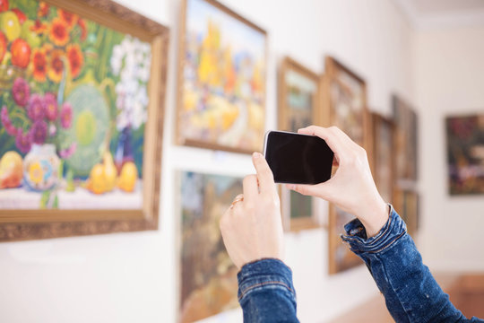 Woman photograph a painting at an exhibition in the art gallery.