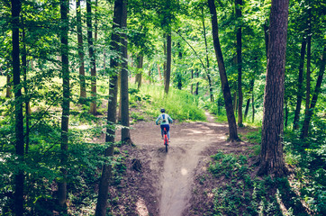 Obraz premium A cyclist in a helmet descends from the mountain on an orange bicycle