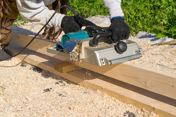 man planing boards with electric tools, chips flying in all directions. Construction, wood processing