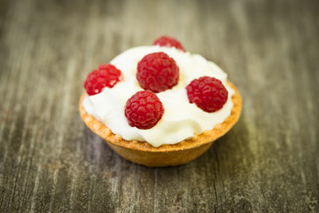 Sweet Delicious Tartlet Cake With Cream And Fresh Berries Of Raspberry On Wooden Table With Texture Close Up.