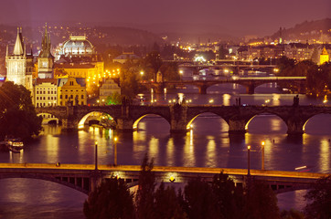 Night view of famous european Prague city - the capital of Czech republic with reflection in river Vltava and historical bridges