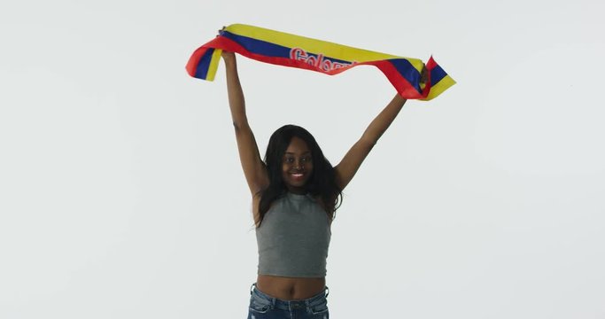 Happy African-American fan holding flag of Colombia celebrating.