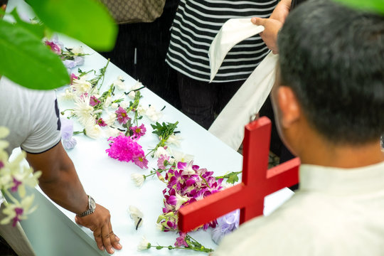 People on funeral Putting Flowers and Earth Soil on Coffin, ASEAN Outdoor Funeral Ceremony.