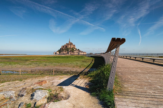 Road to famous Mont Saint Michel abbey. It is one of the most famous tourist attractions in France. Landscape photo during sunrise. Normandy, France