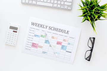 Weekly schedule of manager, office worker, pr specialist or marketing expert. Table with multicolored blocks on white office desk with computer, glasses, calculator top view