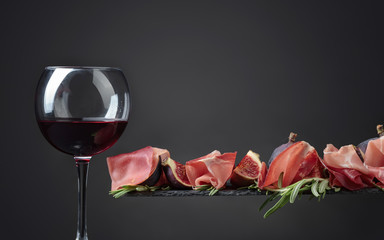 Prosciutto with figs, rosemary and glass of red wine .