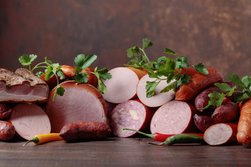 Different sausages and smoked meats on a  wooden table .