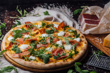 Pizza with ham, parmesan and arugula