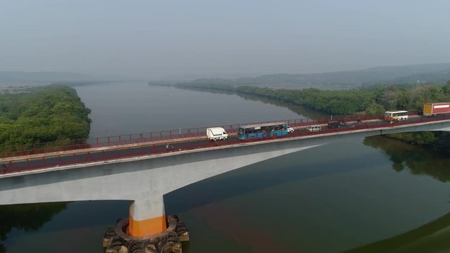 Aerial view. Flying over the bridge, active traffic on a large concrete bridge across the river. Shooting with a drone.