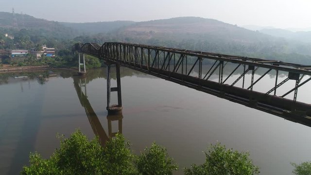 Aerial view. Flying along the long rusty aqueduct truss over the muddy river. 