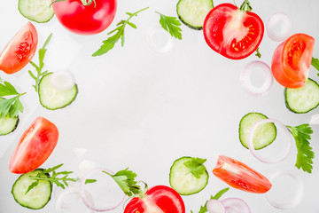 Creative background, layout, concept of fresh healthy diet of salad, fresh raw  vegetables tomatoes parsley onions cucumbers greens, simple pattern on white background