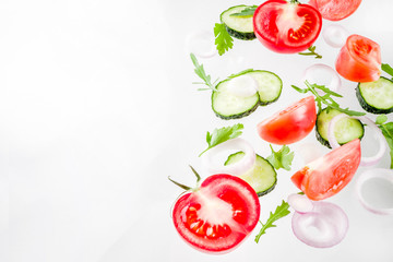 Creative background, layout, concept of fresh healthy diet of salad, fresh raw  vegetables tomatoes parsley onions cucumbers greens, simple pattern on white background