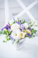 A gentle bouquet of eustoma and other flowers in a light bucket in a light interior.
