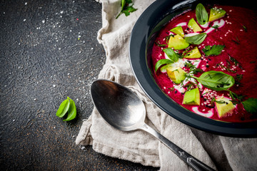 Vegan food, summer cold Beetroot gazpacho soup with lemon, avocado and fresh herbs copy space top view
