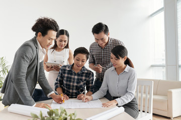 Group of architects working on blueprints together during a meeting